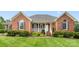 Charming brick home with a welcoming front porch, manicured lawn, and beautiful landscaping at 5410 Berryview Ln, Gastonia, NC 28056