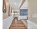 A brightly lit hallway with wooden floors and decorative mirrors on the walls at 7046 North Bridge Dr, Huntersville, NC 28078
