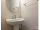 Bathroom featuring a pedestal sink, large round mirror, and chrome fixtures at 709 Volta Nw Dr, Concord, NC 28027