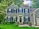 Charming two-story home with black shutters, a well-manicured lawn, and decorative plants at front door at 7344 Maitland Ln, Charlotte, NC 28215