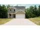 Home exterior with gray roof, tan siding, two stories, large driveway and an attached garage at 7601 Hammond Dr, Charlotte, NC 28215