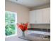 Kitchen with white cabinets, granite countertops, a window, and a clear vase with flowers at 7601 Hammond Dr, Charlotte, NC 28215