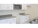 Close-up of a modern kitchen with stainless steel microwave, white cabinets, and granite countertops at 7601 Hammond Dr, Charlotte, NC 28215