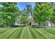 Beautiful lawn with meticulously cut grass and manicured trees leading to the stone facade home at 7916 Deerbridge St, Mint Hill, NC 28227
