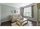 Cozy living room with neutral-toned walls, patterned sofa, and a large window with natural light at 7916 Deerbridge St, Mint Hill, NC 28227