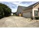 View of the home's exterior featuring a two-car garage and long concrete driveway at 8429 Olde Stonegate Ln, Mint Hill, NC 28227