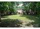 Expansive backyard with lush green grass, mature trees, and a cozy two-story home in the distance at 8618 Rittenhouse Cir, Charlotte, NC 28270