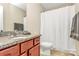 Bathroom features granite countertops, cherry-stained cabinets, toilet, and shower with a white shower curtain at 1397 Tupelo Rd, Clover, SC 29710