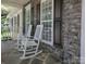 Charming front porch with stone wall, rocking chairs, and large windows with black shutters at 155 Culpeze Rd, Mooresville, NC 28117