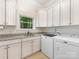 Well-organized laundry room with white cabinets, granite counters, sink and appliances at 3394 Rainbow Dr, Waxhaw, NC 28173