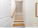 Staircase with hardwood treads, white risers, a wooden handrail, and a white door at 3394 Rainbow Dr, Waxhaw, NC 28173