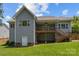 Back exterior of home with well-maintained gray siding, a wooden porch and outdoor stairway, and a neat green lawn at 3633 Longpond Ln, Monroe, NC 28110