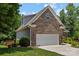 Side view of a brick home with a two-car garage, showcasing well-maintained landscaping at 3633 Longpond Ln, Monroe, NC 28110