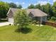 Rear view of the home showing brick exterior and backyard with mature tree at 3633 Longpond Ln, Monroe, NC 28110