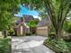 Brick home with an attached garage featuring mature trees, lush landscaping, and a concrete driveway at 5104 Top Seed Ct, Charlotte, NC 28226