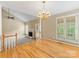 Living room with hardwood floors, a white fireplace, an elegant chandelier, and large windows with shutters at 5104 Top Seed Ct, Charlotte, NC 28226