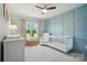 Cozy Bedroom featuring a blue accent wall, crib, glider, changing table, and a bright window at 5334 Orchid Bloom Dr, Fort Mill, SC 29707