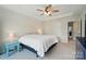 Neutral primary bedroom featuring a tray ceiling, ceiling fan, carpet, and neutral walls with views of the en-suite bathroom at 5334 Orchid Bloom Dr, Fort Mill, SC 29707