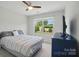 Bright bedroom featuring a ceiling fan, large window with a picturesque view, and a comfortable bed and dresser at 5334 Orchid Bloom Dr, Fort Mill, SC 29707