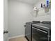 This modern laundry room features a sleek washer and dryer, with shelving for optimal storage solutions at 5334 Orchid Bloom Dr, Fort Mill, SC 29707