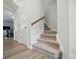 Carpeted stairs with wooden handrail leading to the upper level of the home, featuring hardwood floors and white trim at 5334 Orchid Bloom Dr, Fort Mill, SC 29707