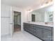 Bright bathroom featuring double vanity with gray cabinets, and an open doorway to the bedroom at 7108 Hambright Rd, Huntersville, NC 28078