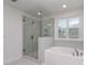 Modern bathroom featuring a glass-enclosed shower and a luxurious soaking tub by a window at 7108 Hambright Rd, Huntersville, NC 28078
