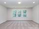 Bright bedroom with three large windows offering a view of lush greenery at 7108 Hambright Rd, Huntersville, NC 28078