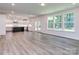 Open-concept living area with hardwood floors, large windows, and modern kitchen with a large kitchen island at 7108 Hambright Rd, Huntersville, NC 28078