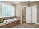 A bathtub with tile surround and unique window offers privacy and natural light at 10501 Olde Irongate Ln, Mint Hill, NC 28227