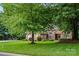 Beautiful red brick home with lush green lawn and mature trees shading the front yard at 10501 Olde Irongate Ln, Mint Hill, NC 28227