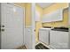 Bright laundry room with white washer, dryer, cabinets, and a convenient exterior door at 10501 Olde Irongate Ln, Mint Hill, NC 28227