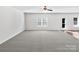 Large living room with gray carpet, neutral walls, a ceiling fan, and a glass door leading to the backyard at 108 Greenway View Ct, Mount Holly, NC 28120