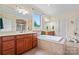 A modern bathroom features double vanities, a soaking tub, and a large window overlooking the yard at 137 Leaning Tower Dr, Mooresville, NC 28117
