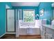 Bright bathroom with tub, shower, window, and vanity, with bright blue walls at 1633 Kiawah Ct, Gastonia, NC 28056