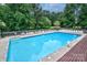 Large community pool surrounded by lounge chairs, umbrellas, and a safety fence, perfect for summer relaxation at 1633 Kiawah Ct, Gastonia, NC 28056
