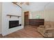 Cozy living room featuring hardwood floors, a white brick fireplace, comfortable seating, and built-in shelves at 1713 Andover Nw St, Concord, NC 28027