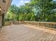 Large wooden deck with a railing, surrounded by lush green trees, perfect for outdoor entertaining at 3124 5Th Street Ne Pl, Hickory, NC 28601