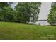 Vast green backyard leading to a tranquil lake, framed by mature trees; perfect for recreation and relaxation at 4920 Surfwood Dr, Sherrills Ford, NC 28673