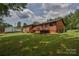 The backyard features a back deck with a set of stairs, a big green grass yard, and a white garage in a wooded area at 4920 Surfwood Dr, Sherrills Ford, NC 28673