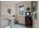 Charming bathroom featuring a pedestal sink, decorative mirror, and a window with a view at 603 S Fulton St, Salisbury, NC 28144