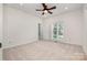 Spacious carpeted bedroom featuring a ceiling fan, natural light, and access to the en suite bath at 6823 Manatee Dr, Concord, NC 28025