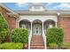 Inviting brick home entrance with stone accents, elegant columns, and manicured shrubs at 6823 Manatee Dr, Concord, NC 28025
