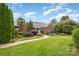 Charming brick home featuring lush landscaping, a decorative pond, and inviting walkway at 6823 Manatee Dr, Concord, NC 28025