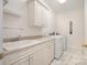 Well-lit laundry room with white cabinets, marble floors, and a utility sink at 6823 Manatee Dr, Concord, NC 28025