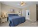 Bedroom features a large window, ceiling fan, blue bedding, and access to bathroom at 6908 Beamish Pl, Mint Hill, NC 28227