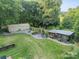 Aerial view of a spacious backyard with a greenhouse, chicken coop, and manicured lawn at 7901 Bud Henderson Rd, Huntersville, NC 28078
