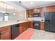 Traditional kitchen design with wood cabinets and black appliances, including range, microwave and refrigerator at 13604 Morehouse St, Huntersville, NC 28078