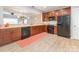 Open kitchen showcasing wood cabinets, sleek black appliances, and light wood-look flooring, blending style and functionality at 13604 Morehouse St, Huntersville, NC 28078