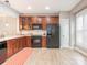 Bright kitchen boasts wood cabinets, black appliances, and light-colored flooring, complemented by a subway tile backsplash and natural light at 13604 Morehouse St, Huntersville, NC 28078